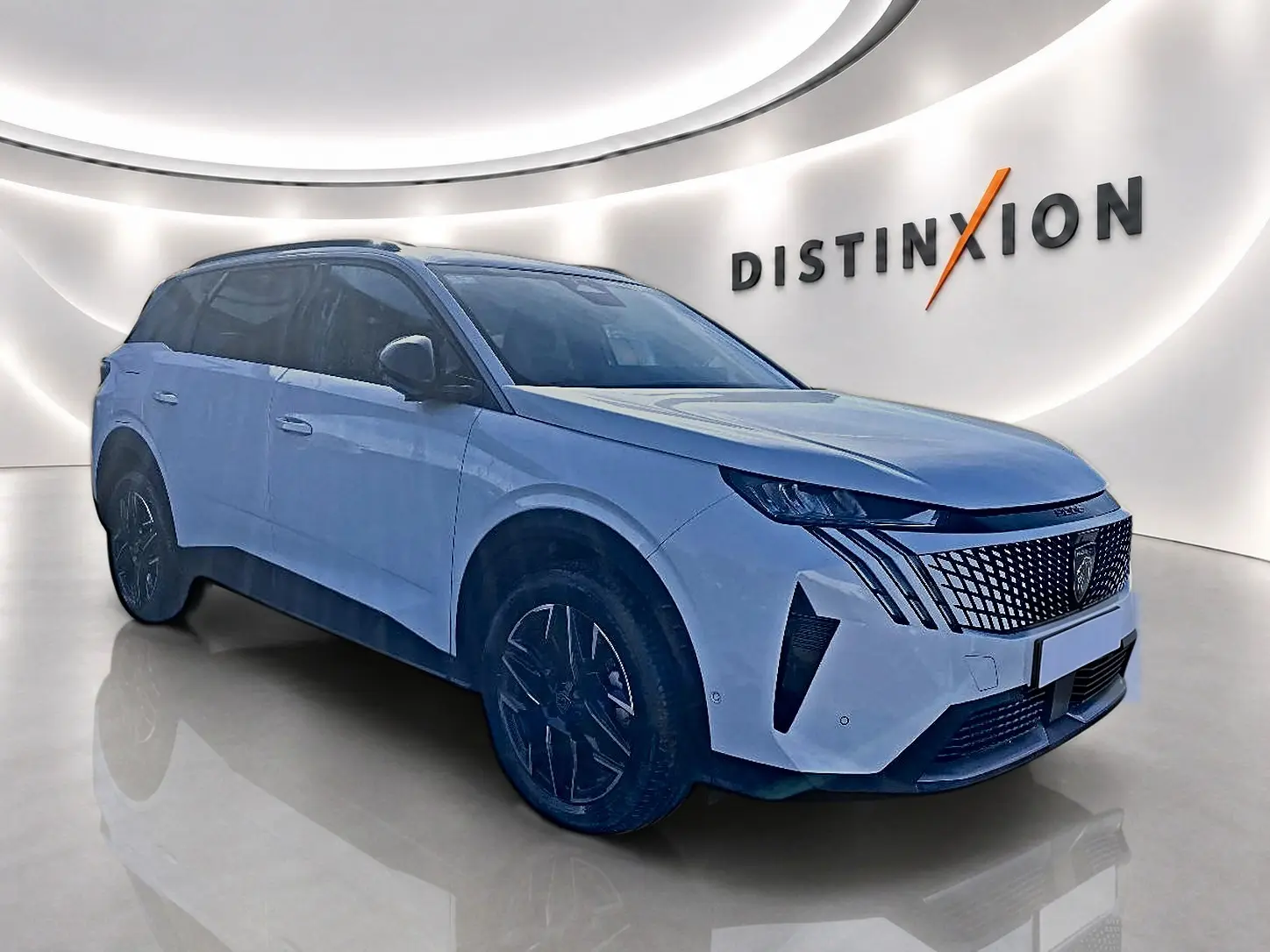 Peugeot 5008 blanc en 3/4 avant droit dans un showroom avec calandre distinctive et jantes noires.