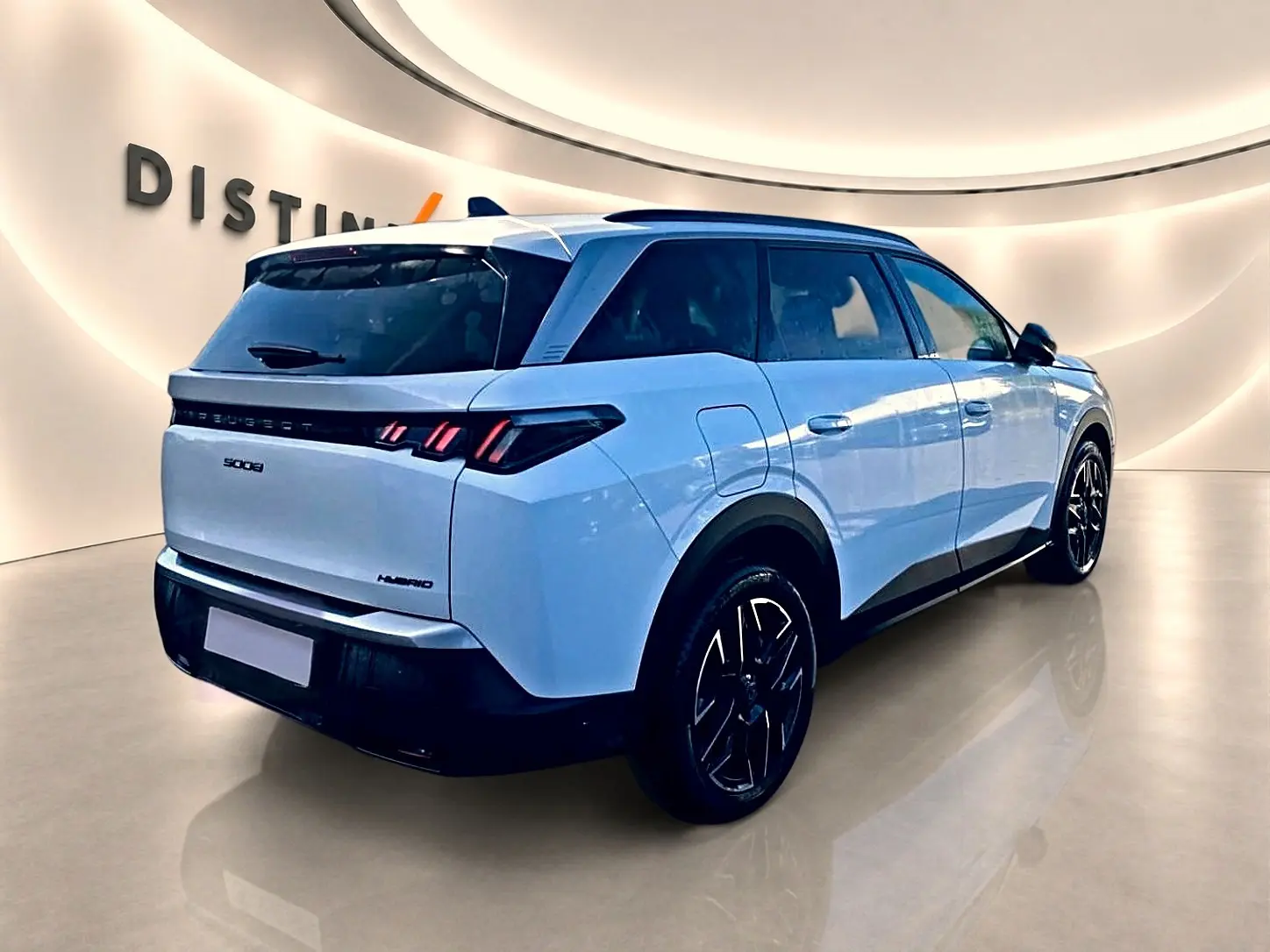 Vue 3/4 arrière droite d’un Peugeot 5008 Hybrid blanc avec jantes noires et feux arrière LED distinctifs.