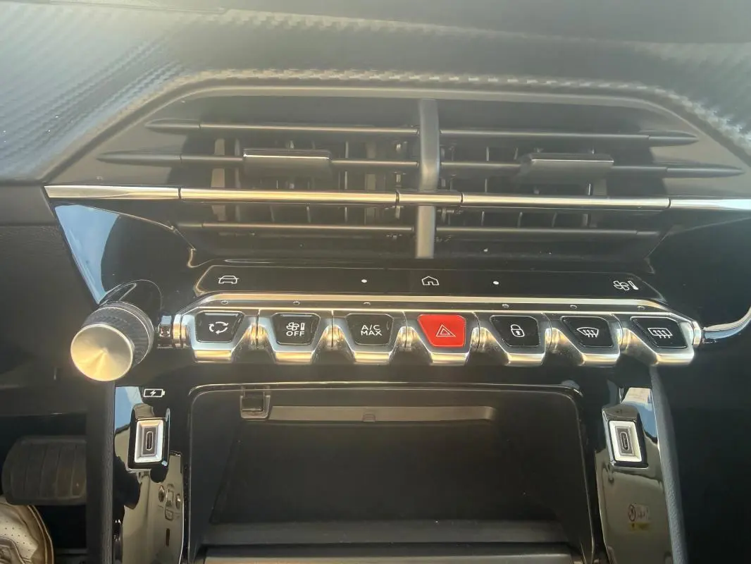 Vue rapprochée de la console centrale du Peugeot 208 Hybrid 110 e-DCS6 Allure 2024, avec boutons de commande et aérateurs noirs.