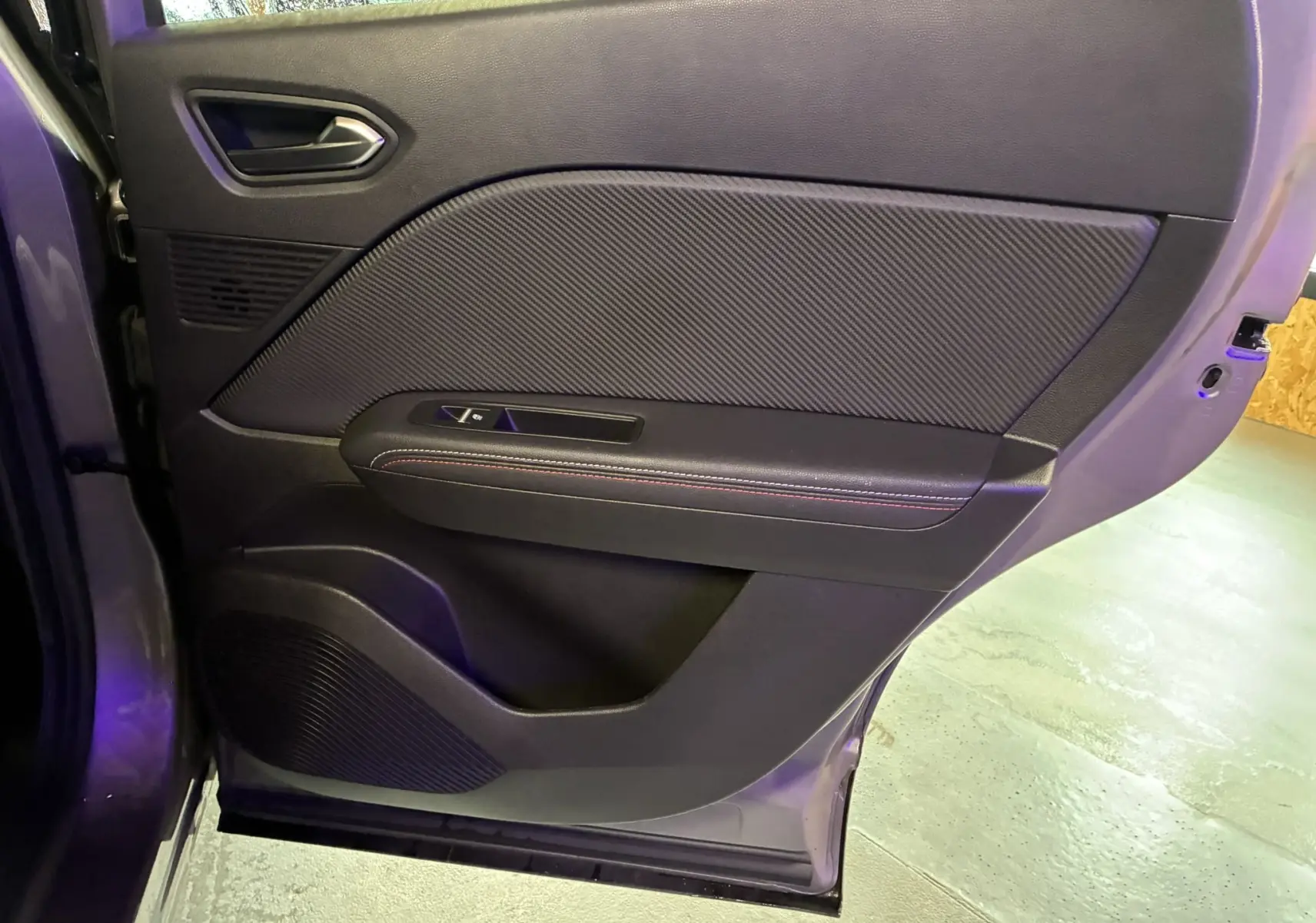 Vue rapprochée de la porte arrière gauche gris foncé du Renault Captur 1.3 TCE 140 EDC RS Line avec garniture tissu et surpiqûres rouges.