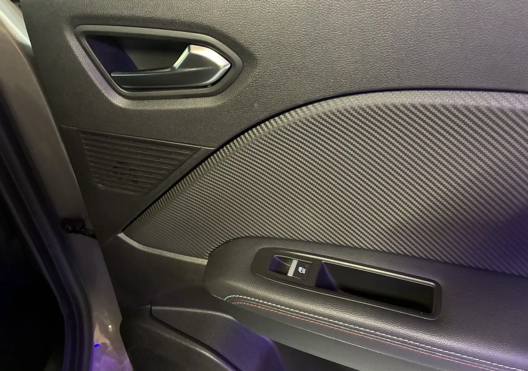 Détail de la porte intérieure côté gauche du Renault Captur gris 2021, avec poignée argentée et insert effet carbone.