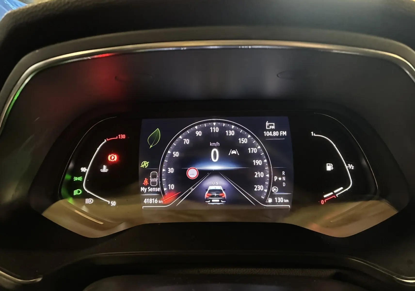 Vue rapprochée du tableau de bord numérique du Renault Captur gris, affichant la vitesse à 0 km/h et divers indicateurs.