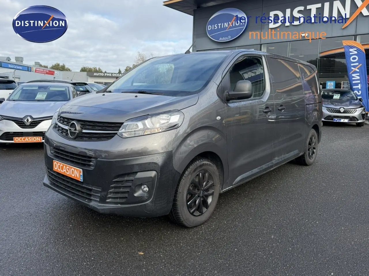 Opel Vivaro Fourgon gris Pierre de Lune métallisé vu en 3/4 avant droit avec jantes noires et calandre noire.