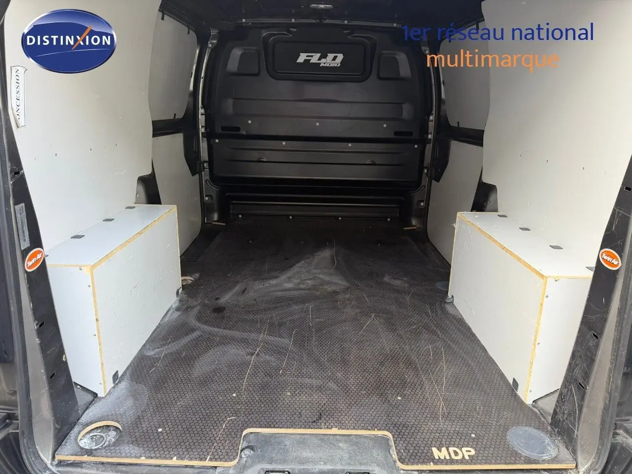 Vue intérieure arrière du fourgon Opel Vivaro gris, montrant l'espace de chargement avec planchers et protections latérales blanches.