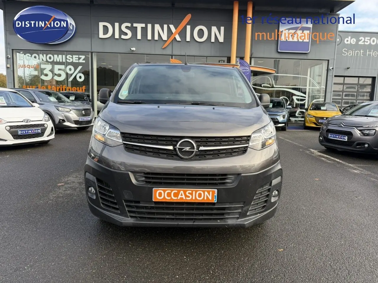 Vue frontale d'un Opel Vivaro Fourgon gris Pierre de Lune métallisé avec plaque "OCCASION" sur fond neutre.