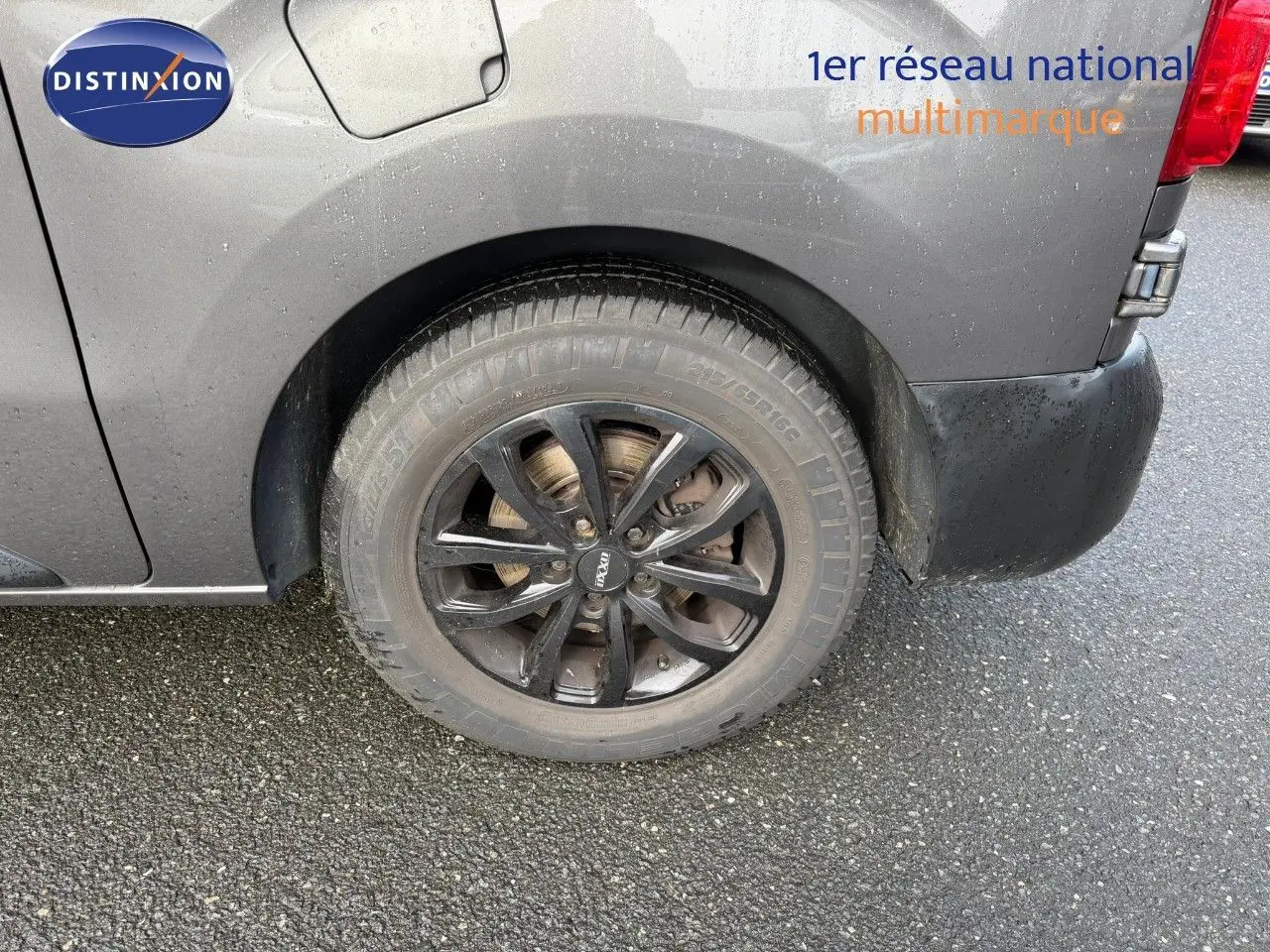 Gros plan sur la roue arrière droite noire du fourgon Opel Vivaro gris Pierre de Lune métallisé.