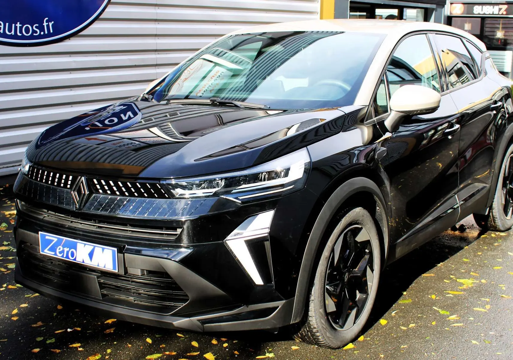 Renault Captur 2025 noir métal et toit gris en 3/4 avant droit, avec calandre lumineuse et jantes noires biton.