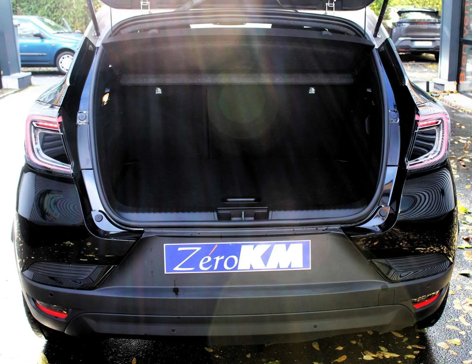 Vue arrière d'un Renault Captur noir métal avec coffre ouvert et toit gris visible en partie supérieure.