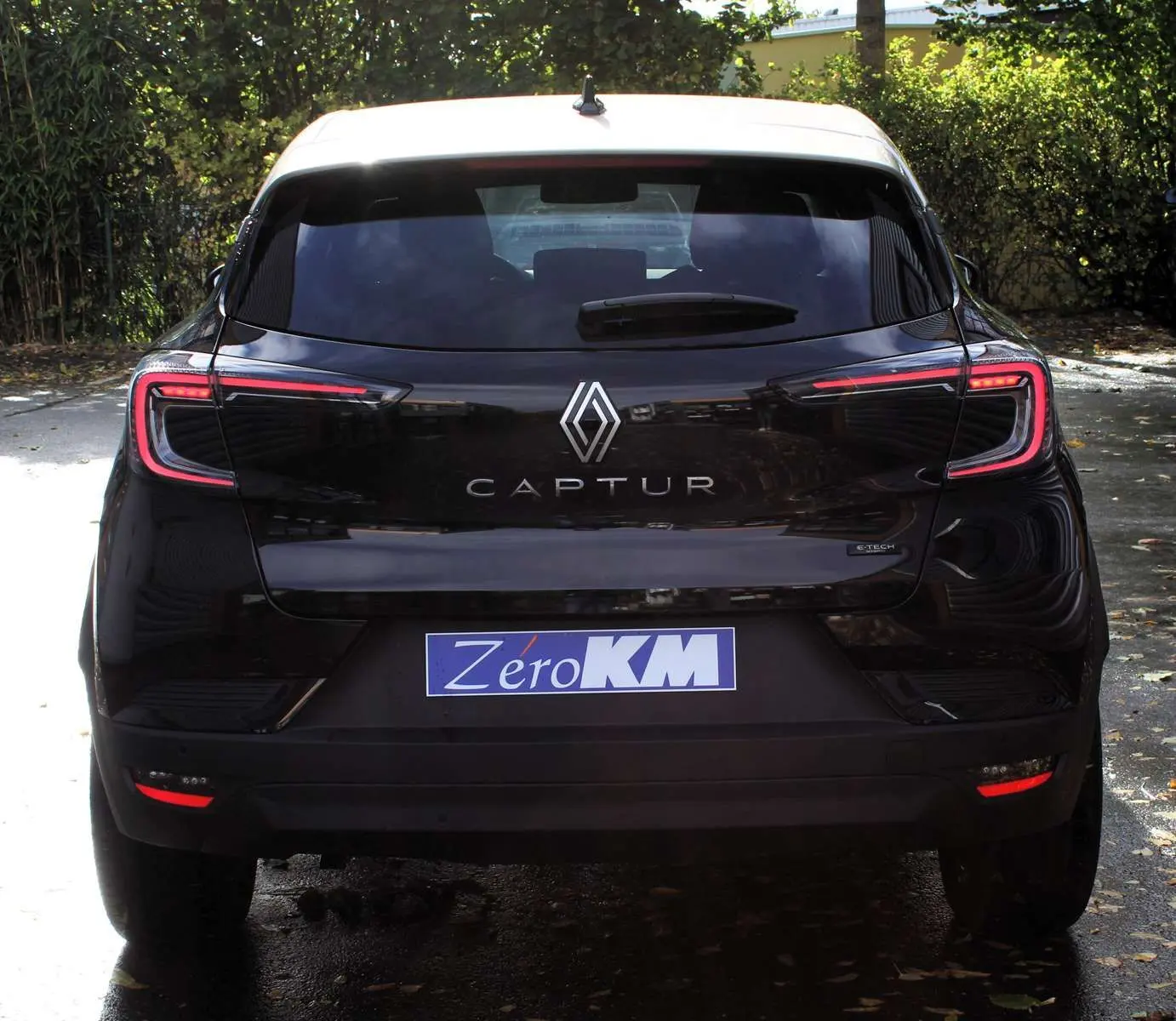 Vue 3/4 arrière droite du Renault Captur noir métal avec toit gris, jantes biton et feux arrière LED distinctifs.