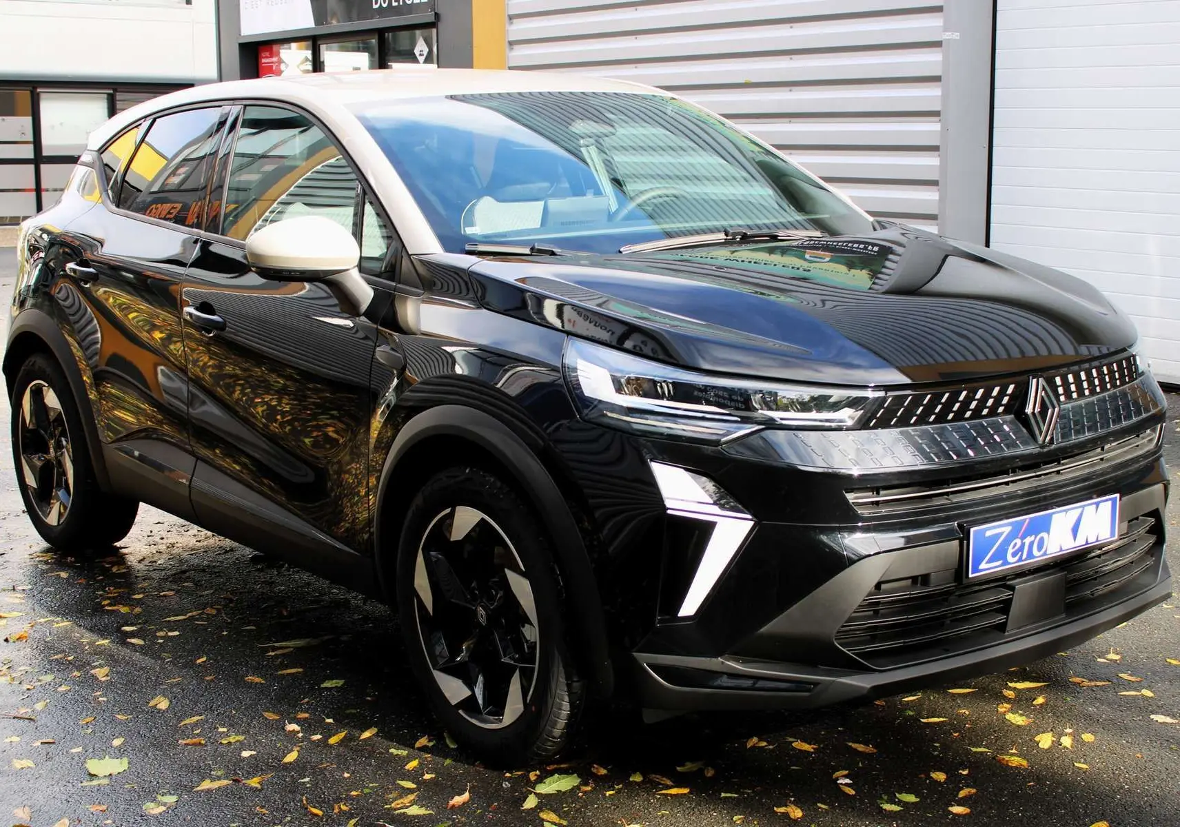 Renault Captur 2025 noir métal avec toit gris, vue 3/4 avant droit, feux LED et jantes bi-ton distinctives.