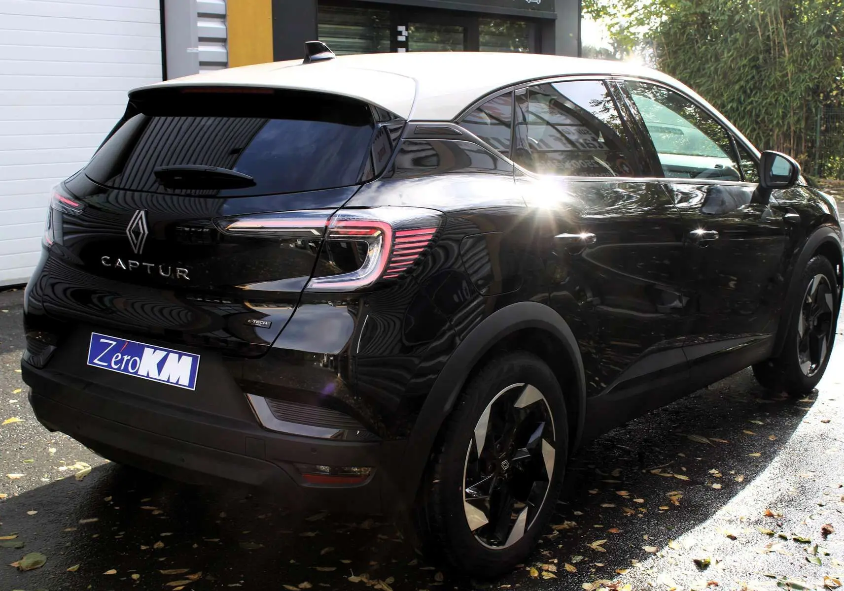 Vue 3/4 arrière droite d'un Renault Captur noir métal avec toit gris, jantes bi-ton et feux arrière LED distinctifs.