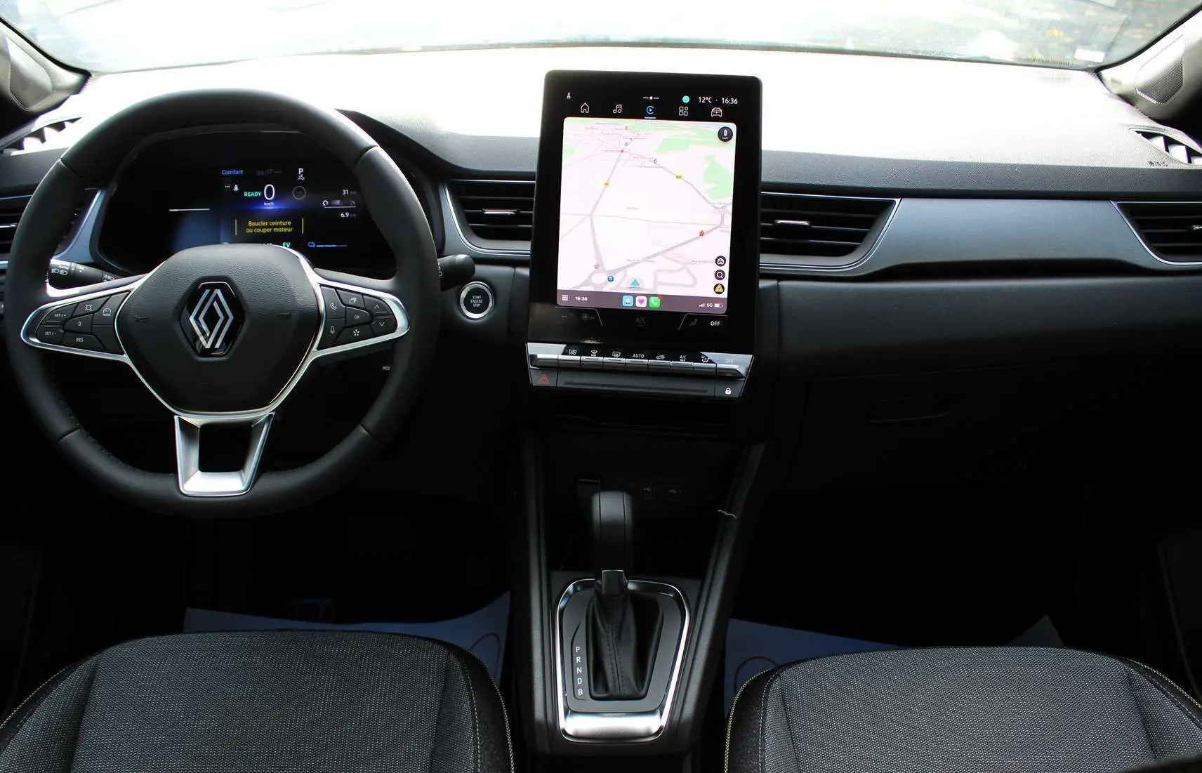 Intérieur du Renault Captur 2025, vue de face sur le volant, écran tactile central et console de boîte automatique.