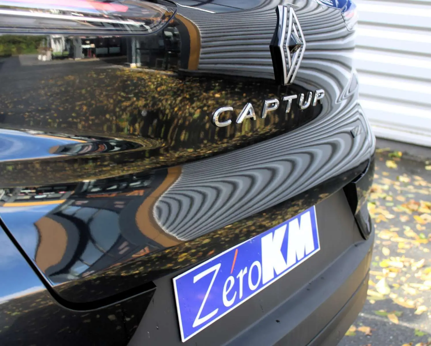 Gros plan sur l'écusson E-TECH Hybrid sur la carrosserie noire métal du Renault Captur 2025.