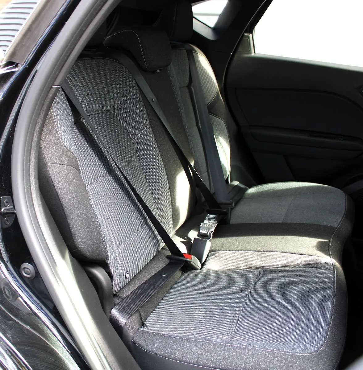 Vue intérieure des sièges arrière gris foncé du Renault Captur 2025, avec ceintures de sécurité noires visibles.