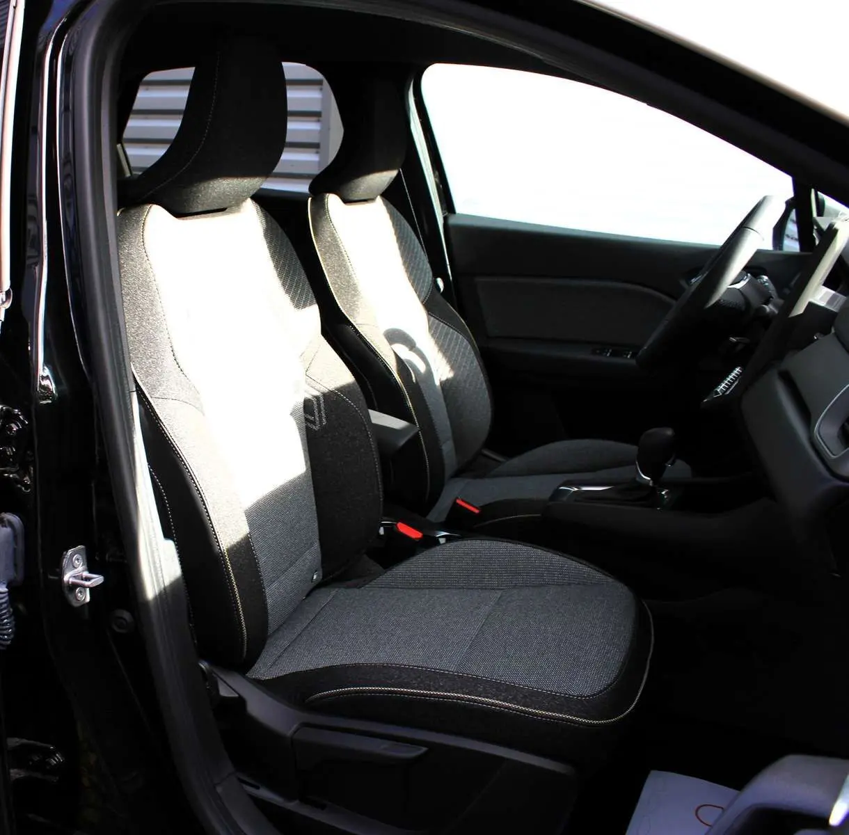 Intérieur du Renault Captur 2025 vu côté gauche, sièges tissu gris et noir avec surpiqûres contrastées.