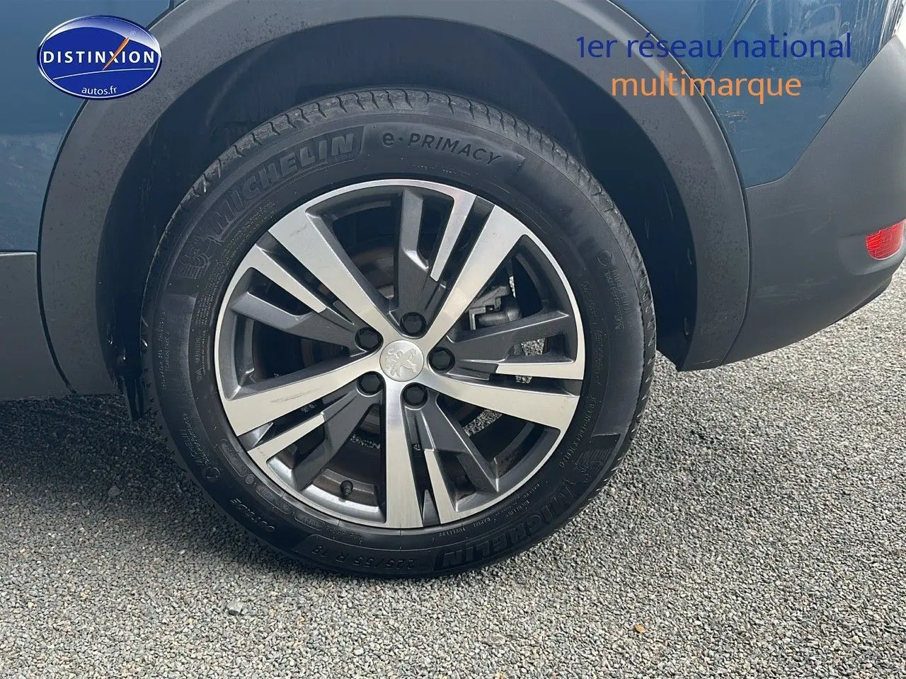 Gros plan sur la roue arrière droite d’un Peugeot 5008 bleu avec jante alliage 18 pouces et logo lion au centre.