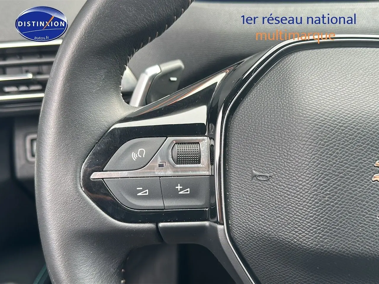 Gros plan sur le volant cuir noir du Peugeot 5008 bleu 2024 avec commandes audio intégrées côté gauche.