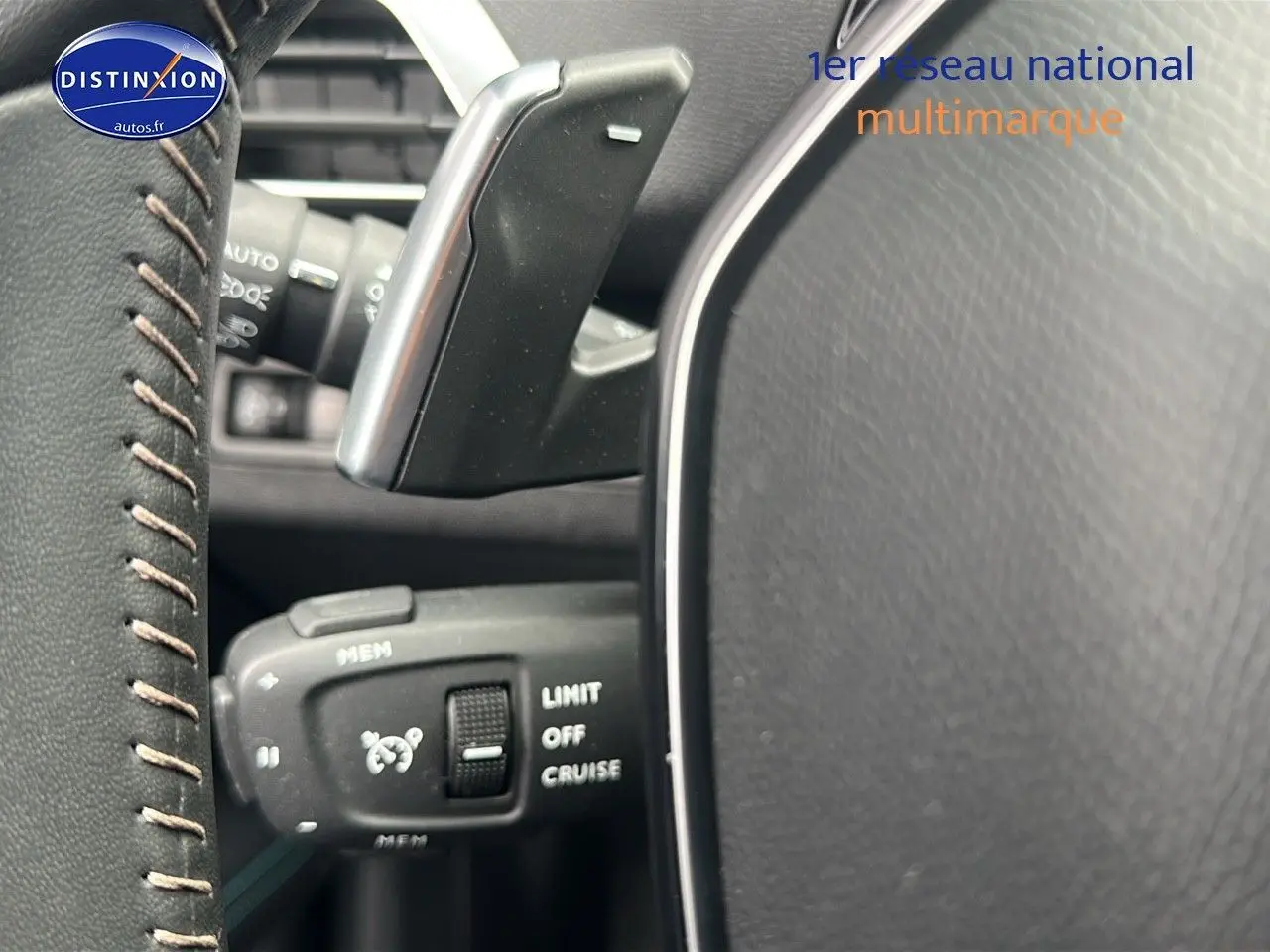 Gros plan sur la commande de régulateur de vitesse au volant cuir noir du Peugeot 5008 bleu 2024.