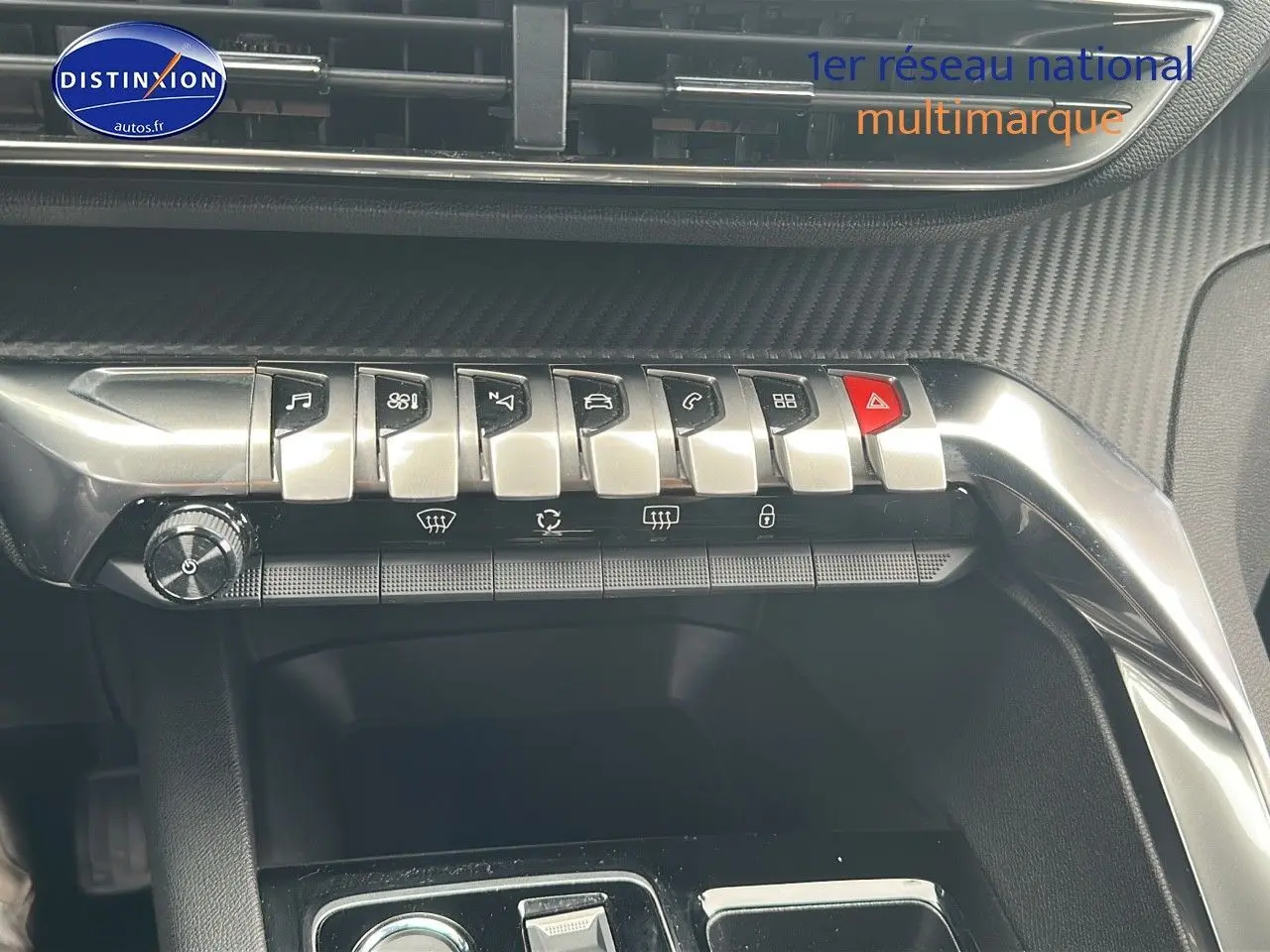 Gros plan sur la console centrale du Peugeot 5008 bleu 2024, mettant en valeur les commandes chromées et le design carbone.
