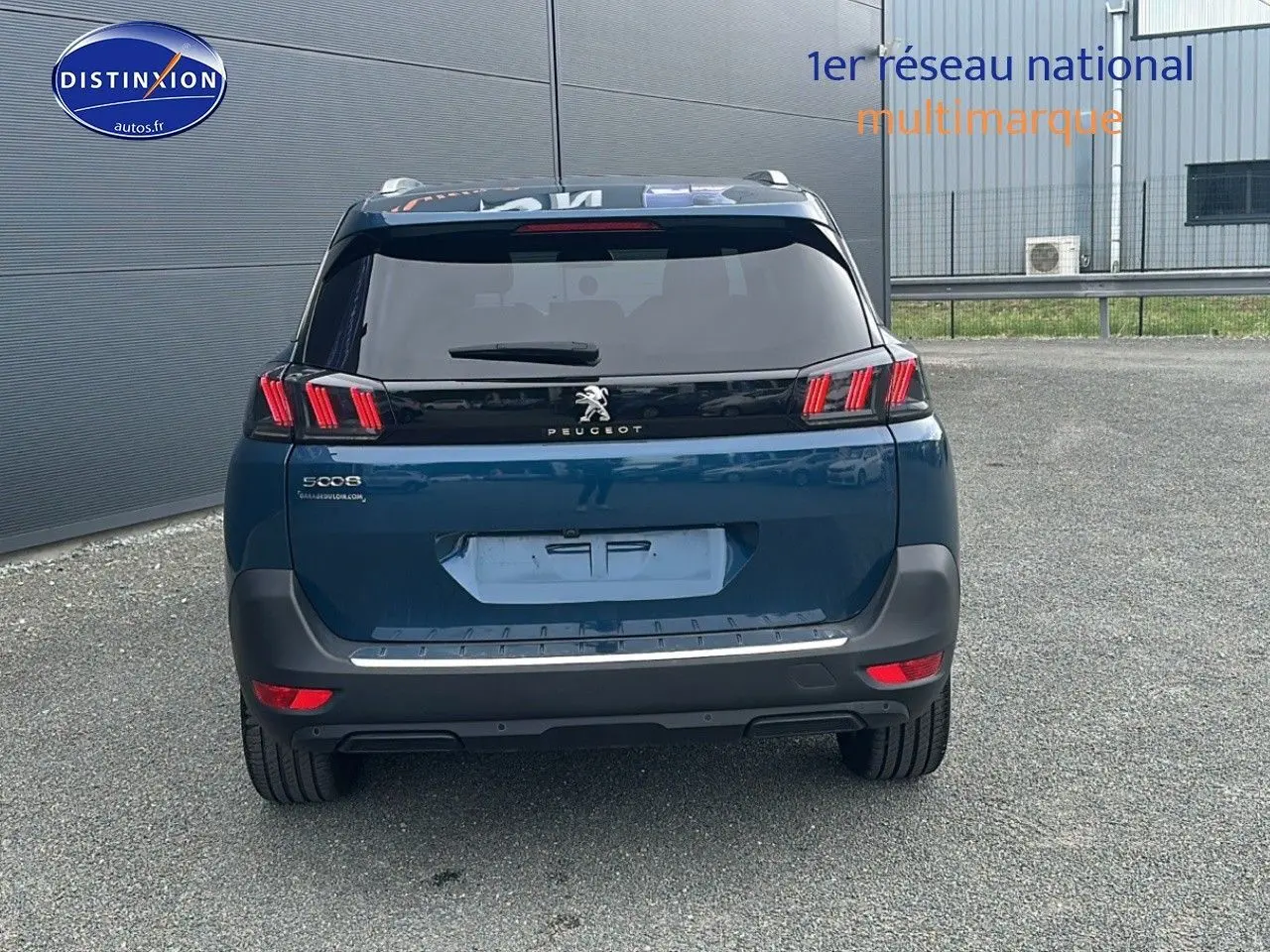 Vue arrière d'un Peugeot 5008 bleu 2024 avec feux LED à effet 3D et barres de toit en aluminium visibles.