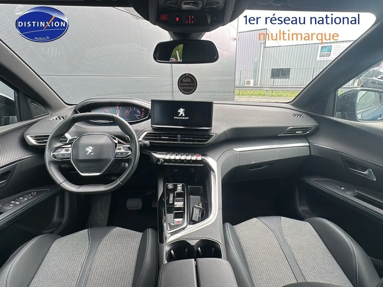 Habitacle avant du Peugeot 5008 2024 avec tableau de bord noir et écran tactile central affichant le logo Peugeot.