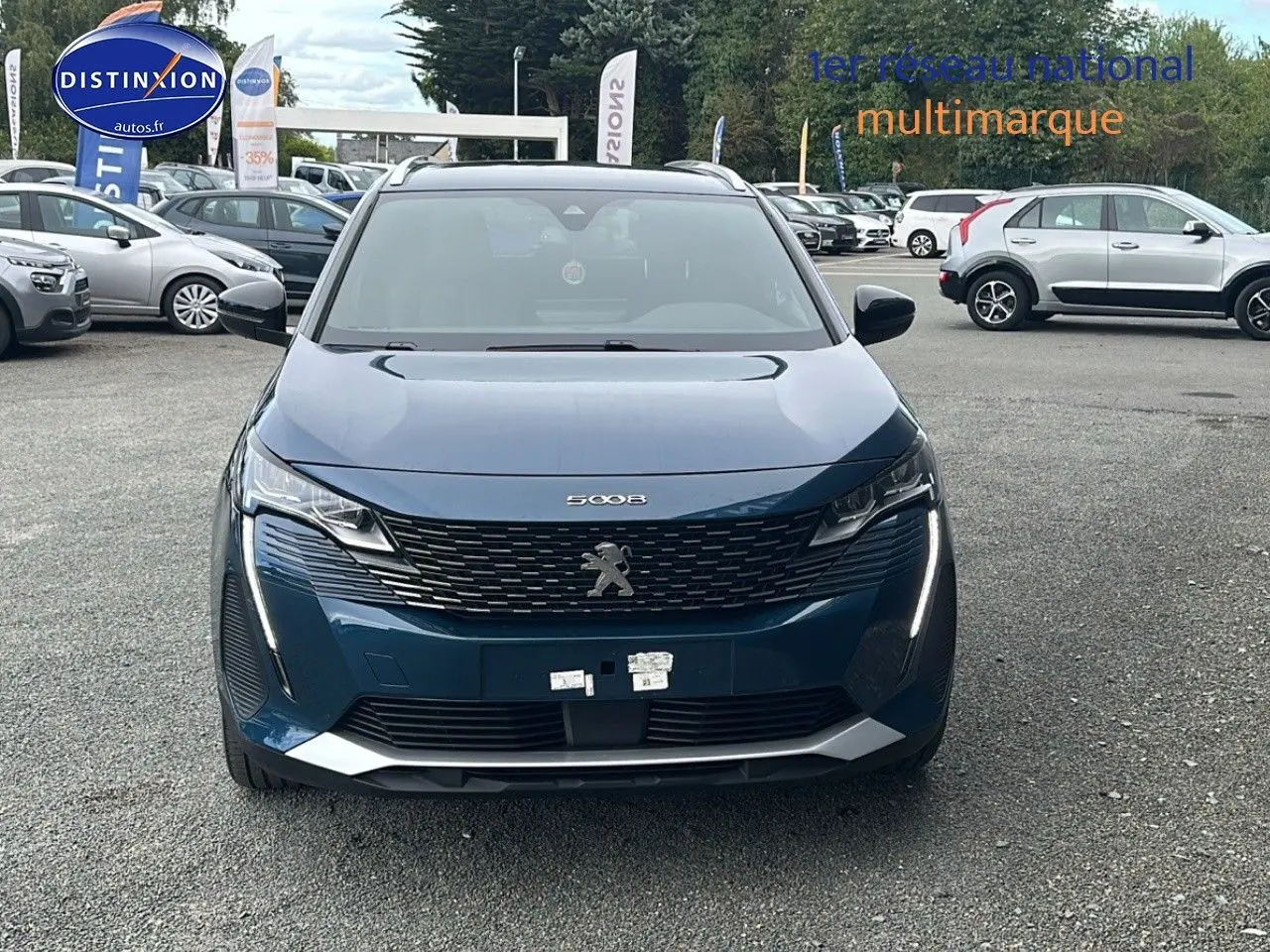 Vue frontale d'un Peugeot 5008 bleu 2024 avec calandre à damiers chromés et feux LED à effet 3D.
