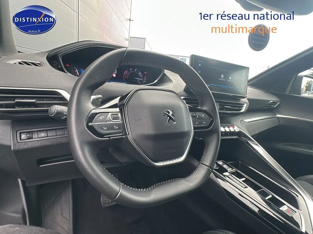 Vue intérieure du poste de conduite du Peugeot 5008 bleu, volant compact et écran tactile central visible.