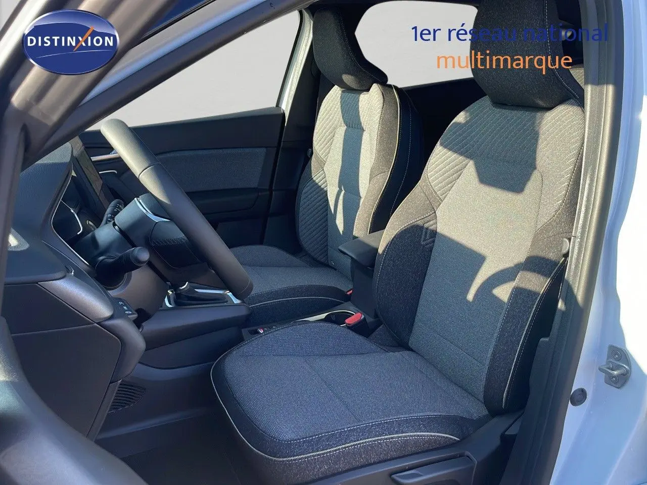 Intérieur du Renault Captur E-Tech 2025, vue côté gauche sur les sièges tissu noir et gris, porte blanche ouverte.