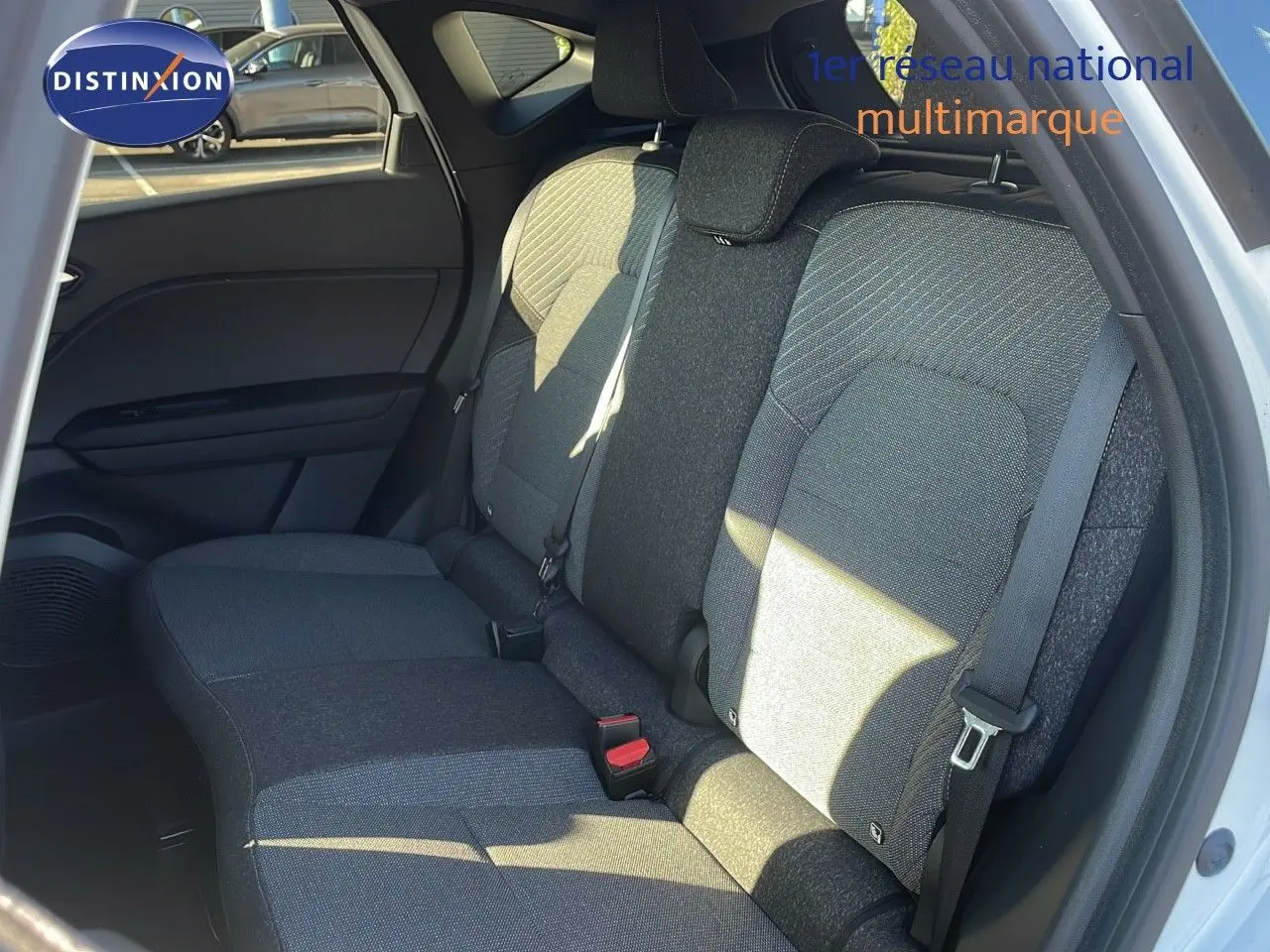 Vue intérieure des sièges arrière en tissu gris du Renault Captur E-Tech hybride blanc nacré avec toit noir, porte ouverte côté droit.