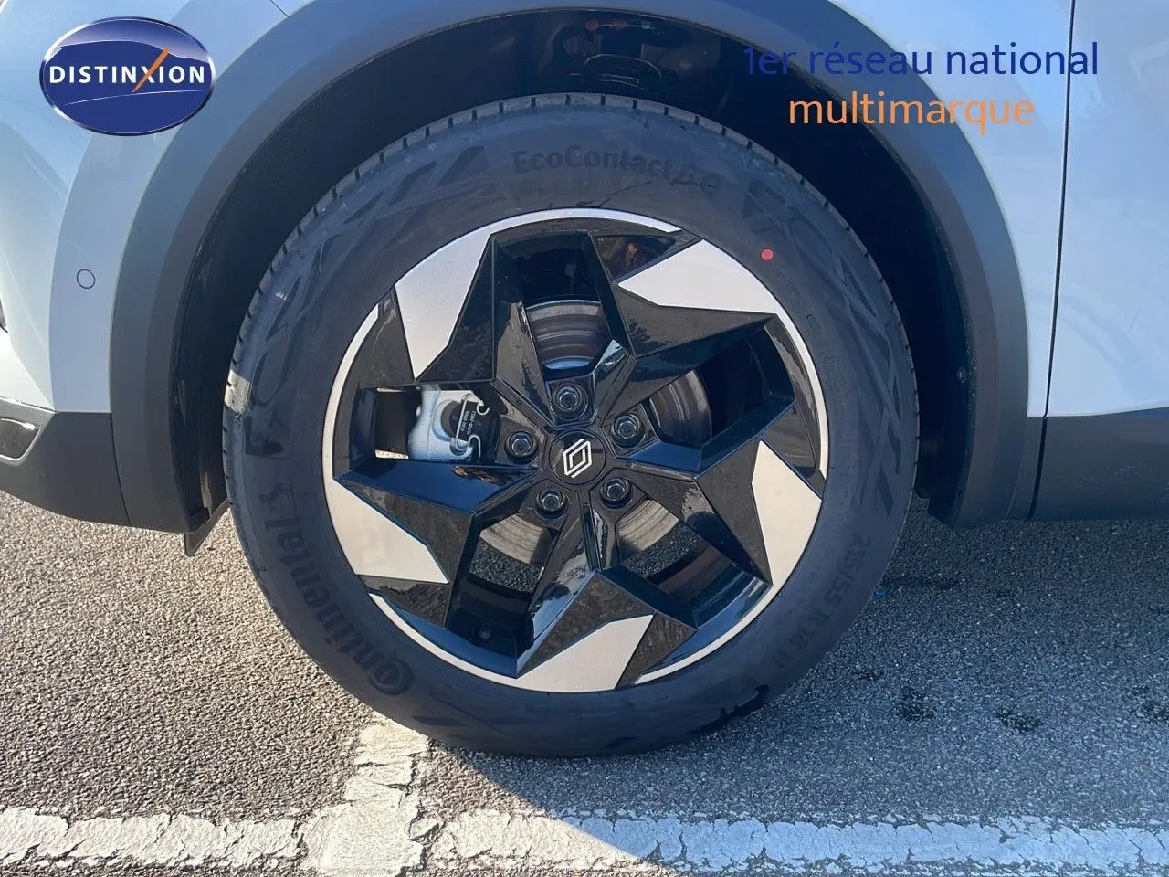 Gros plan sur la roue avant gauche du Renault Captur blanc nacré avec jante noire et argentée au design étoilé.