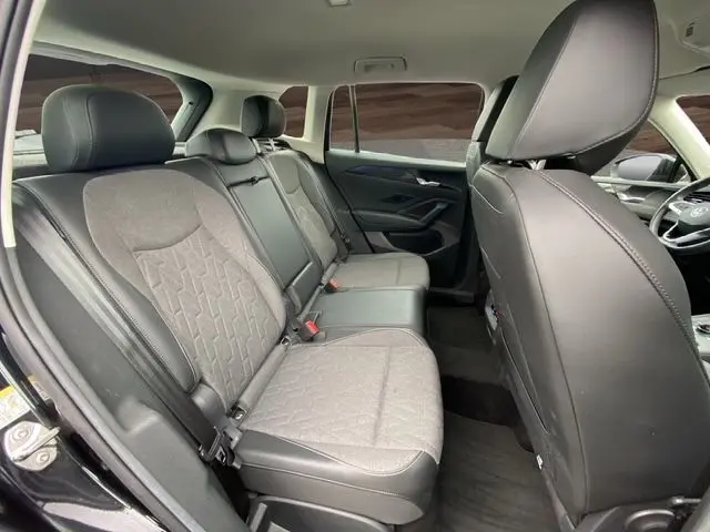 Vue intérieure arrière du Volkswagen Tiguan noir 2024, sièges tissu gris-noir avec appuie-têtes et ceintures visibles.