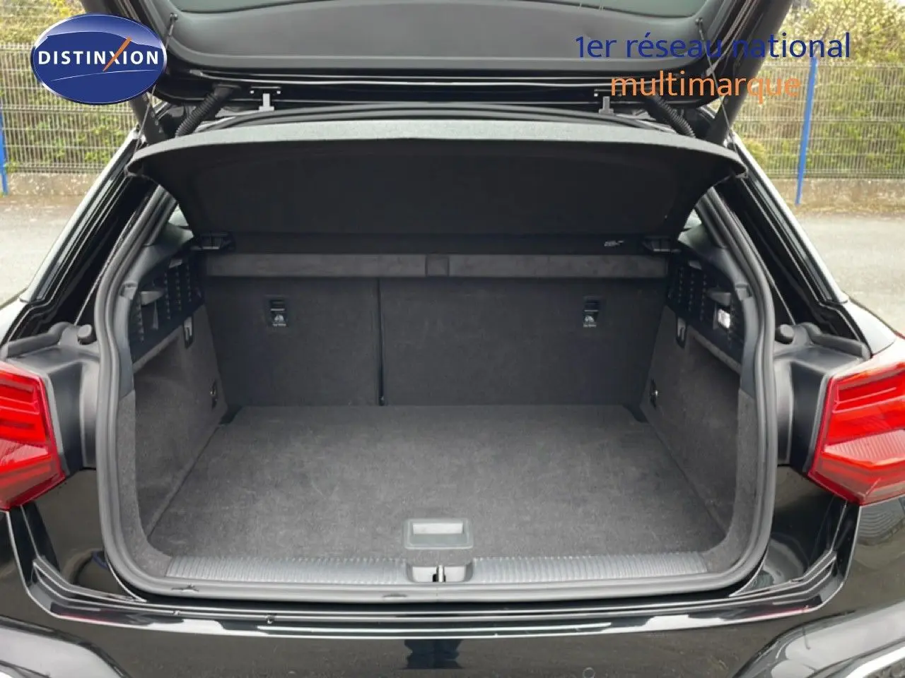Coffre ouvert vu de l'arrière d'un Audi Q2 noir mito metal, montrant un espace de chargement propre et spacieux.