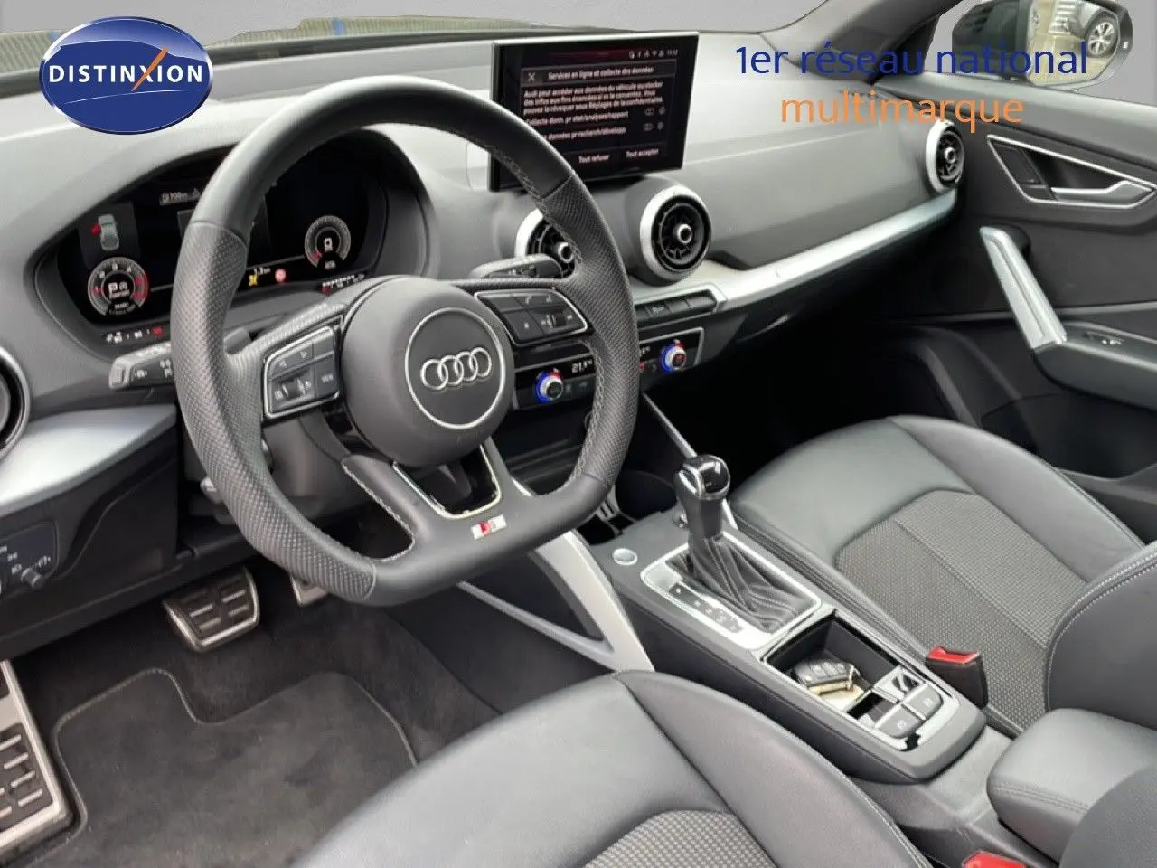 Vue intérieure côté conducteur de l'Audi Q2 35 2.0 TDI S-Line 2025, avec volant cuir perforé et tableau de bord digital.