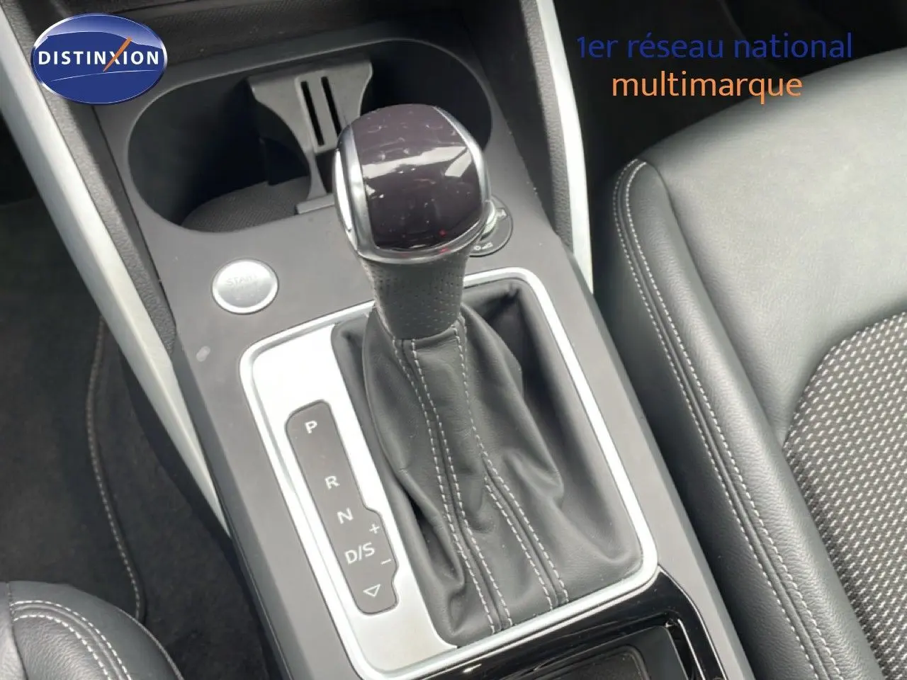 Gros plan sur la console centrale de l’Audi Q2 noire, mettant en valeur le levier de vitesses automatique et les sièges en cuir.