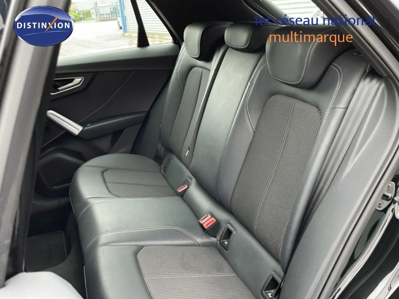 Vue côté gauche des sièges arrière en cuir noir de l'Audi Q2 2025 finition S-Line, avec ceintures rouges visibles.