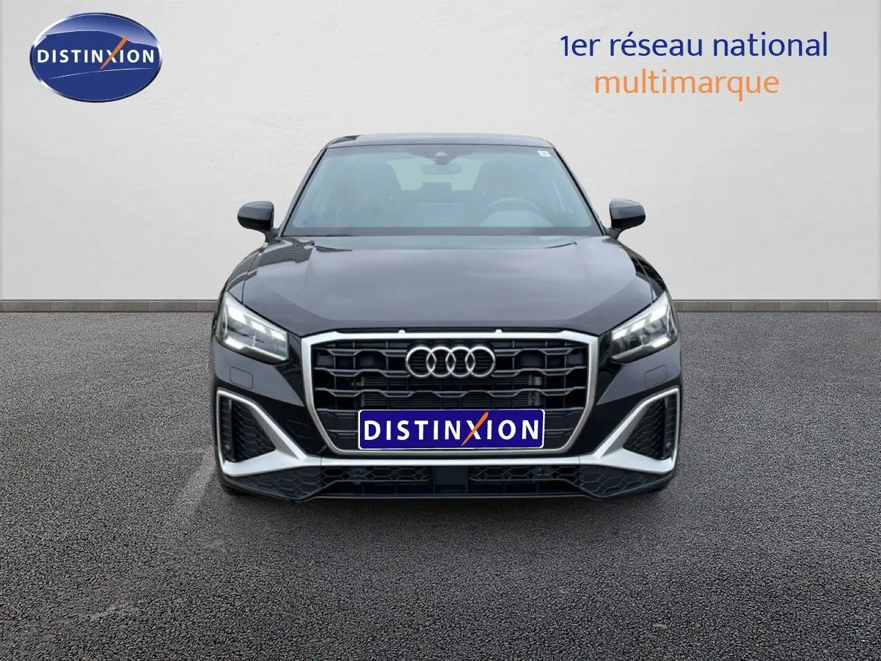 Vue frontale d'un Audi Q2 noir mito metal 2025 avec calandre hexagonale et phares LED allumés.