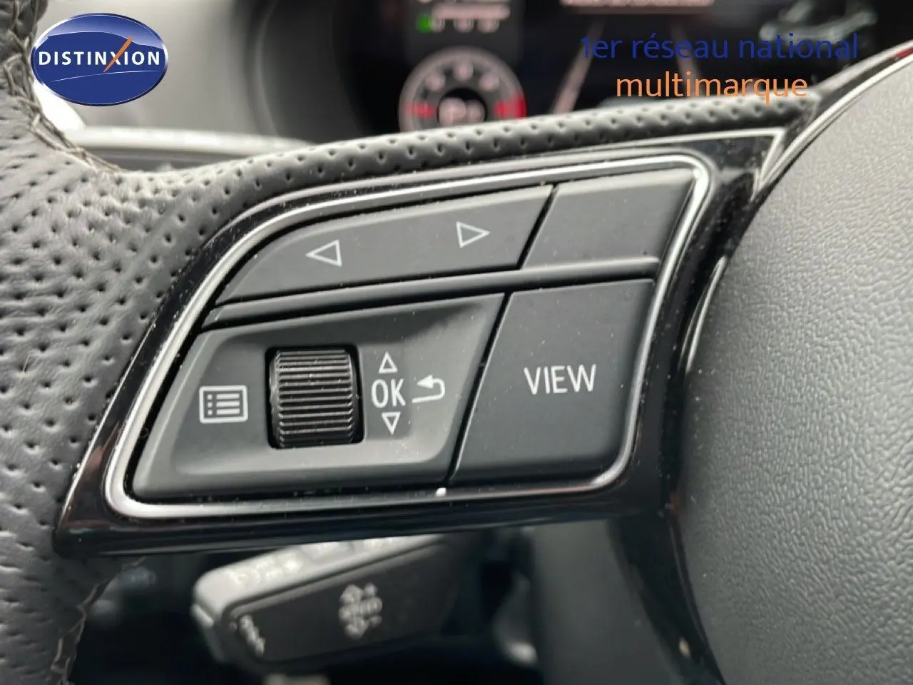 Gros plan sur les commandes multifonctions noires du volant perforé d’un Audi Q2 35 2.0 TDI S-Line 2025.