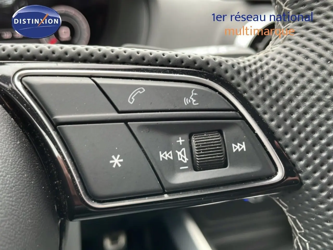 Gros plan sur les commandes audio et téléphone au volant en cuir perforé noir de l'Audi Q2 noir mito metal.