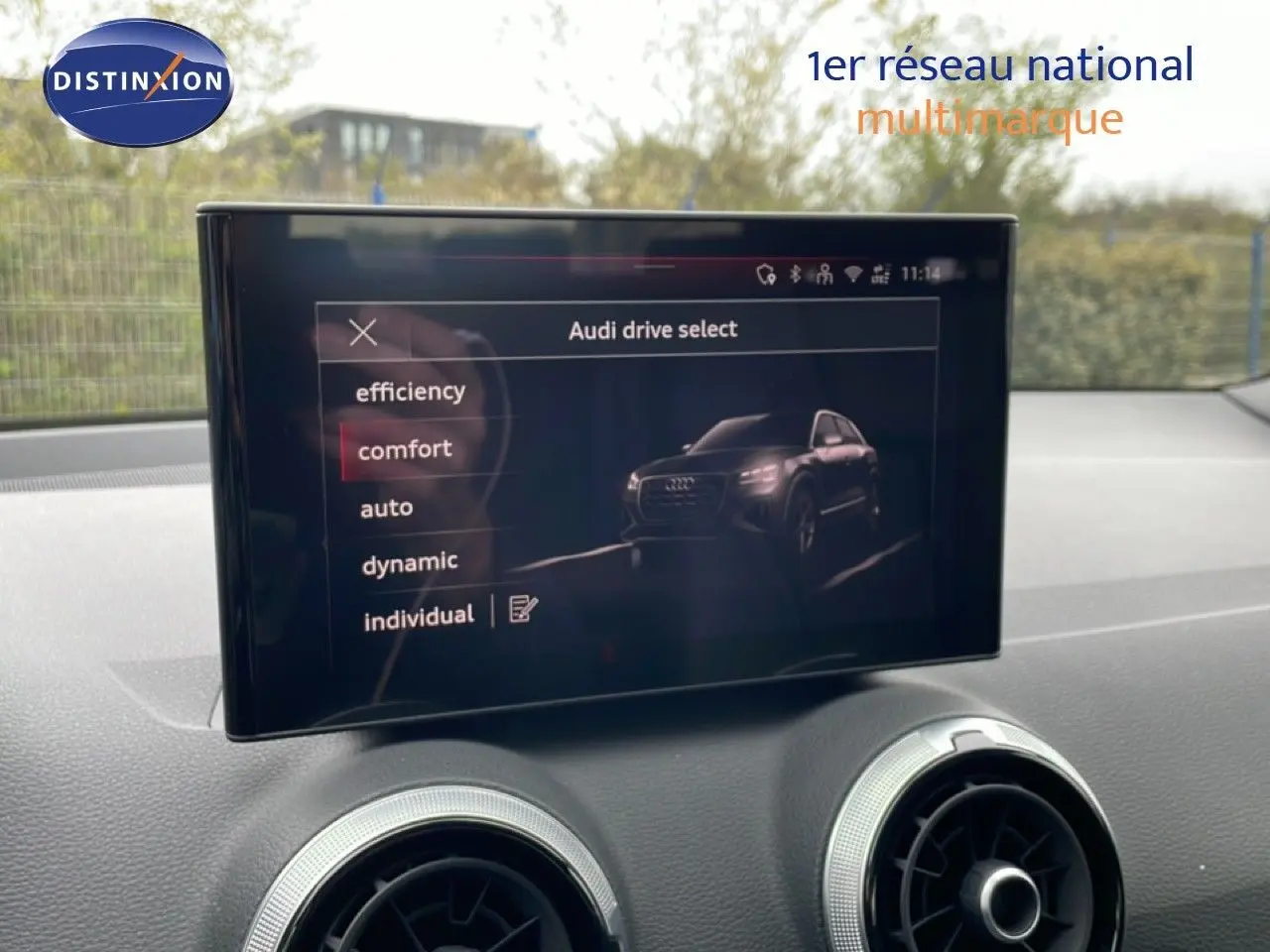 Écran central affichant le menu Audi drive select avec une image du SUV Audi Q2 noir mito metal en vue 3/4 avant.