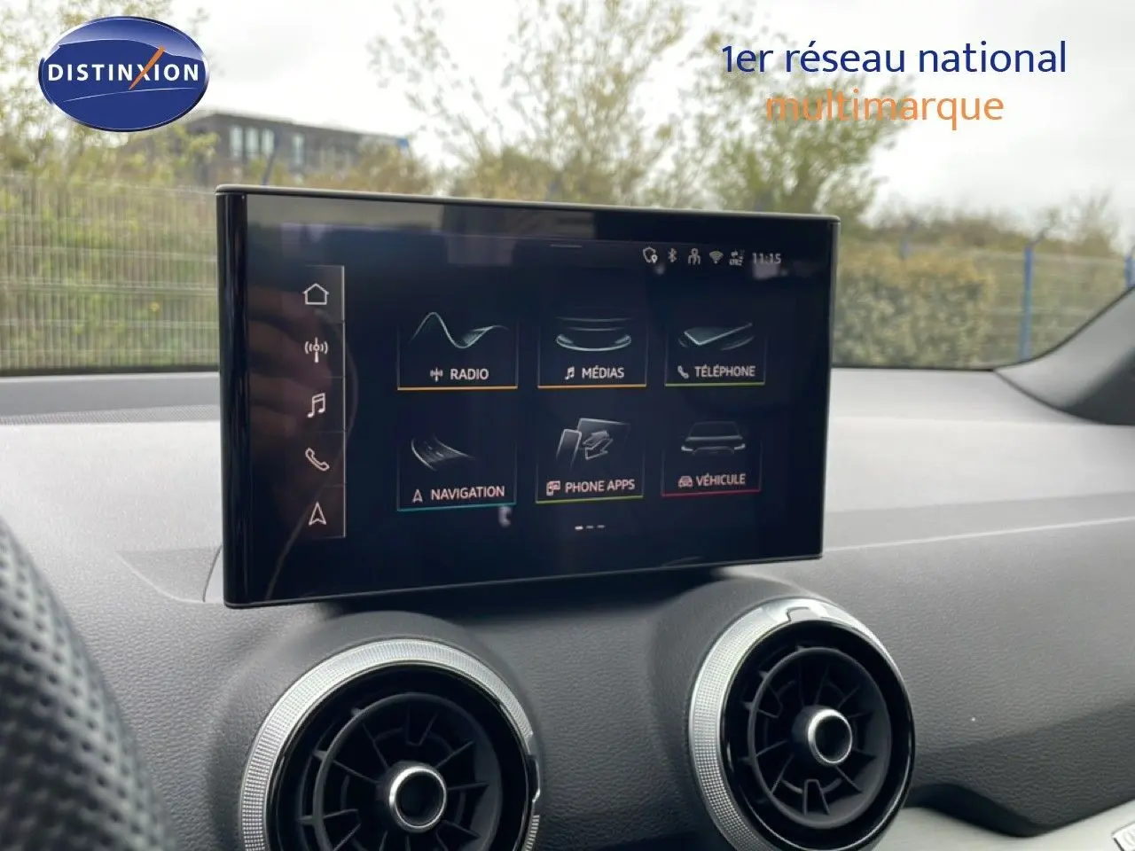 Écran tactile central de l’Audi Q2 noir mito métal, vue intérieure sur la console avec aérateurs ronds argentés.