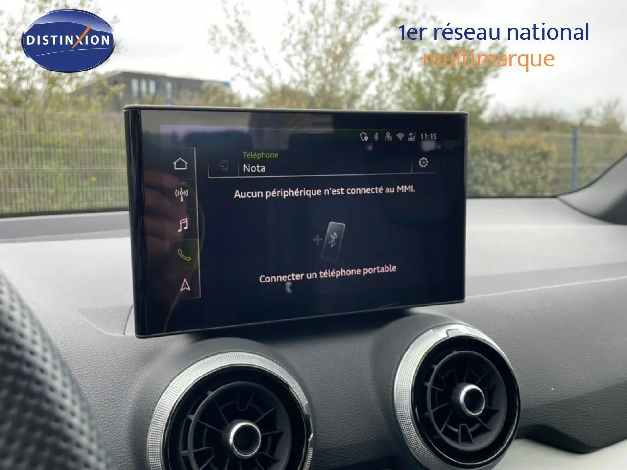 Écran central tactile et aérateurs ronds du tableau de bord d’un Audi Q2 noir mito metal, vue intérieure avant.