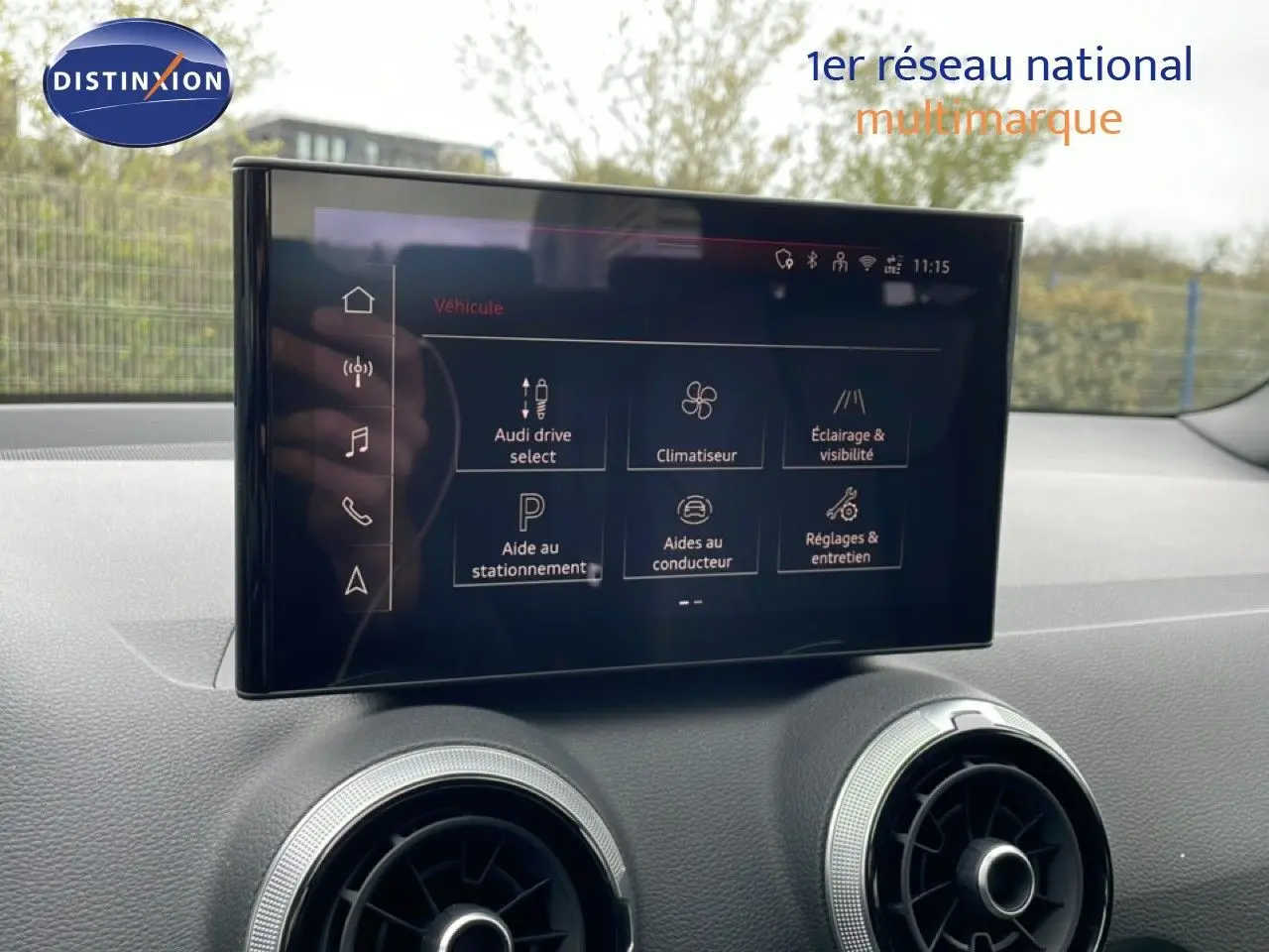 Écran tactile central affichant les options du véhicule dans l'habitacle d'un Audi Q2 noir, vue de face.