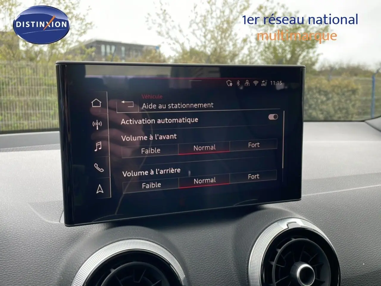 Écran tactile central de l'Audi Q2 noir mito metal, affichant les réglages d'aide au stationnement et volume audio.