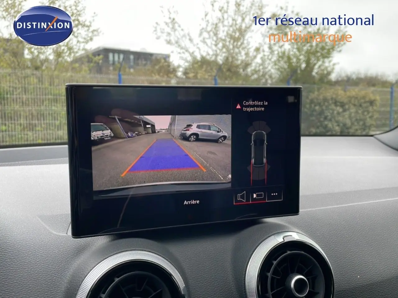 Vue intérieure sur l'écran multimédia affichant la caméra de recul de l'Audi Q2 noir mito metal, avec tableau de bord et aérateurs visibles.
