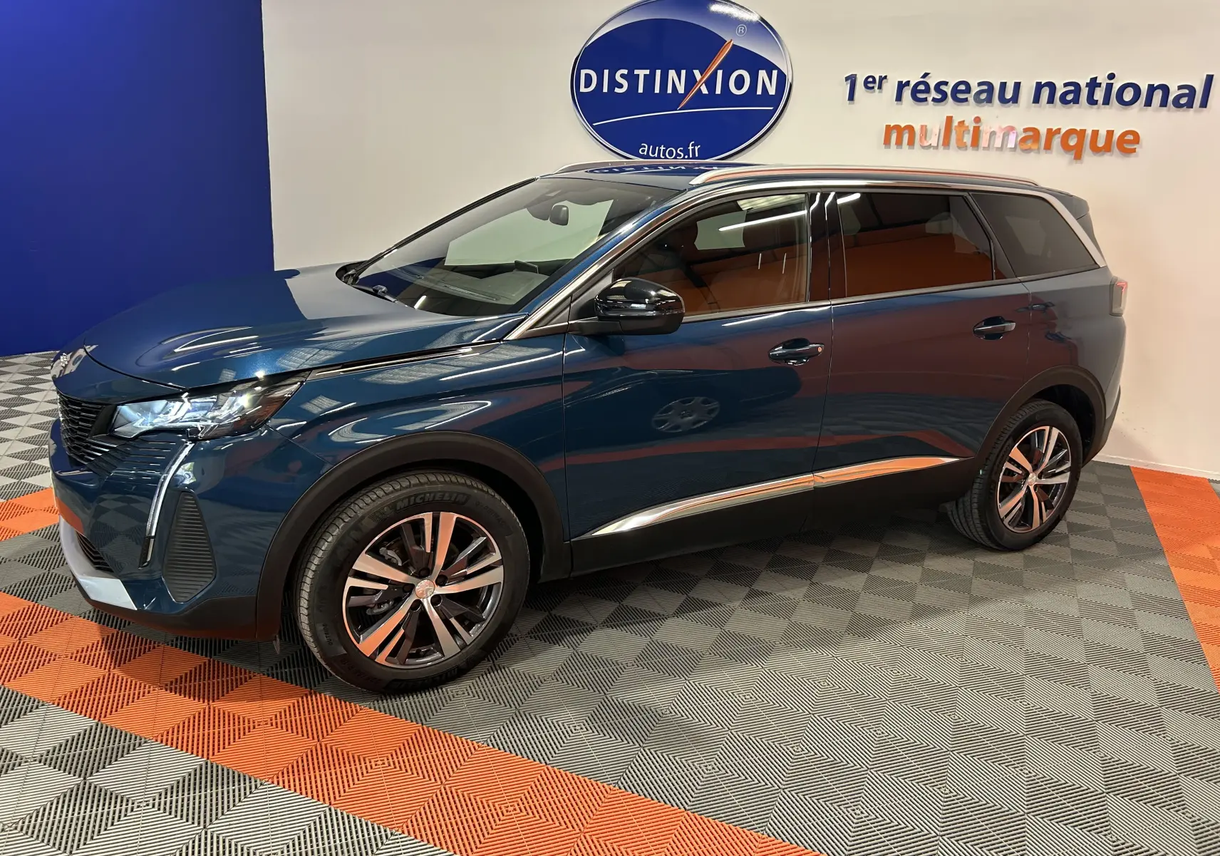 Peugeot 5008 bleu Célèbes en vue 3/4 avant droit, avec jantes alliage et intérieur marron visible.