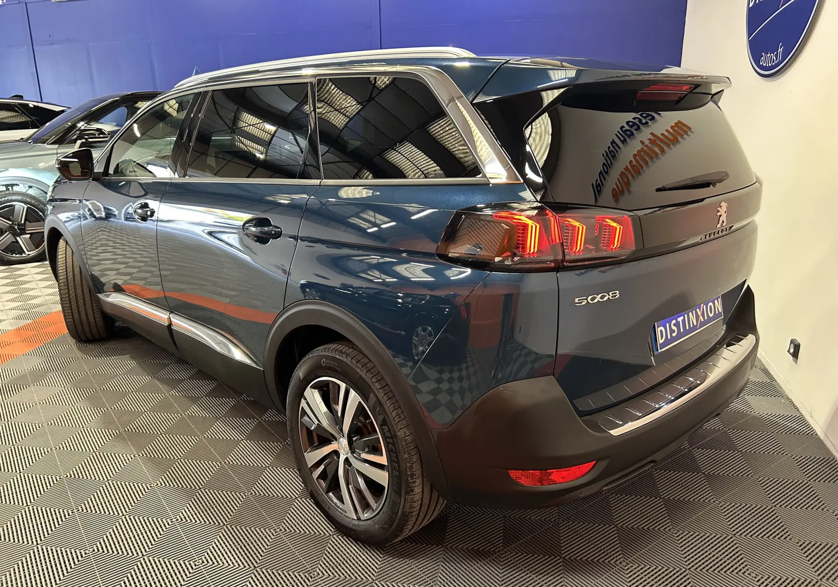 Vue 3/4 arrière droite d’un Peugeot 5008 bleu Célèbes avec feux arrière LED et jantes alliage en showroom.