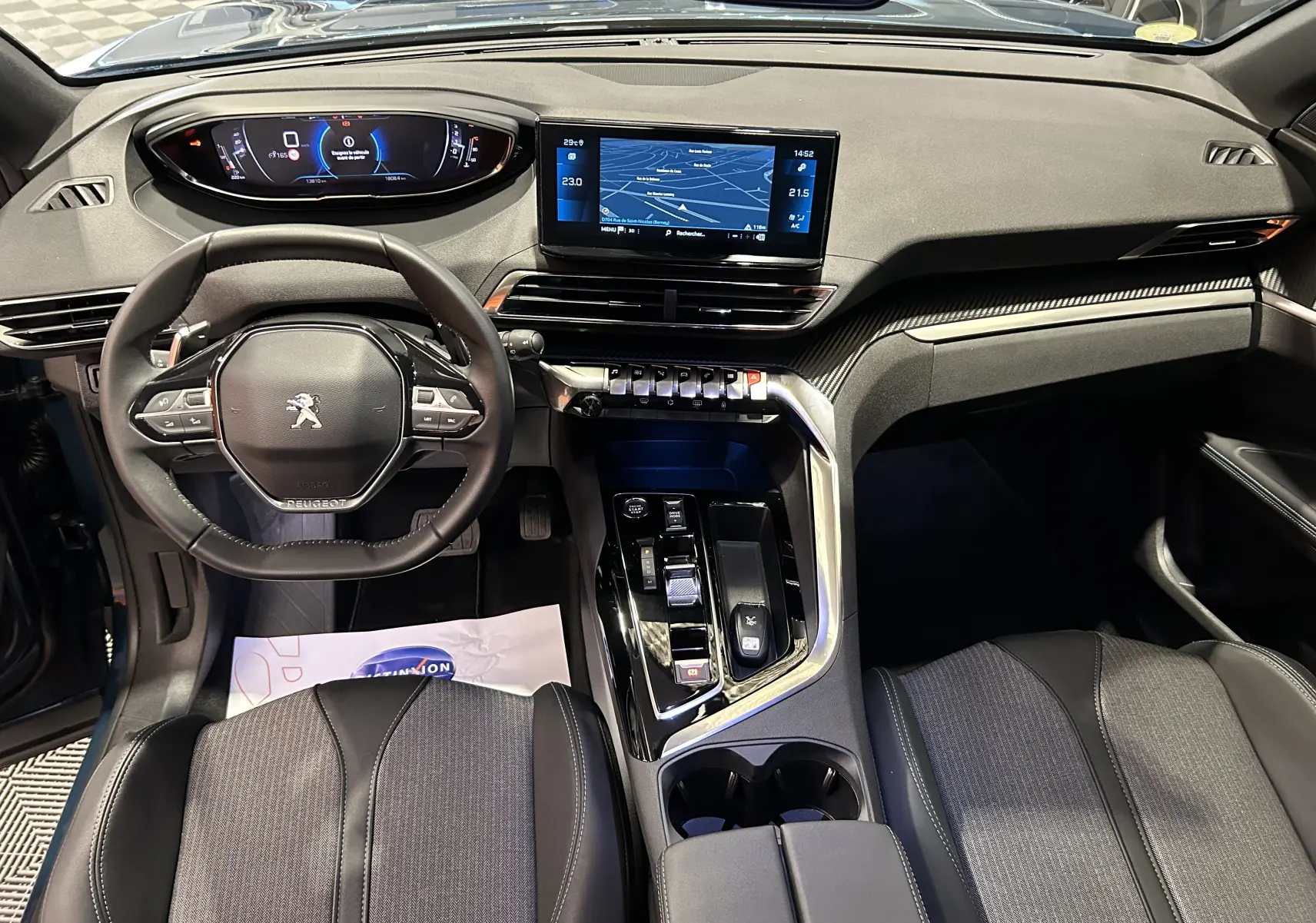 Vue intérieure avant du Peugeot 5008 2024 avec tableau de bord numérique et écran central tactile, sièges noirs et détails argentés.