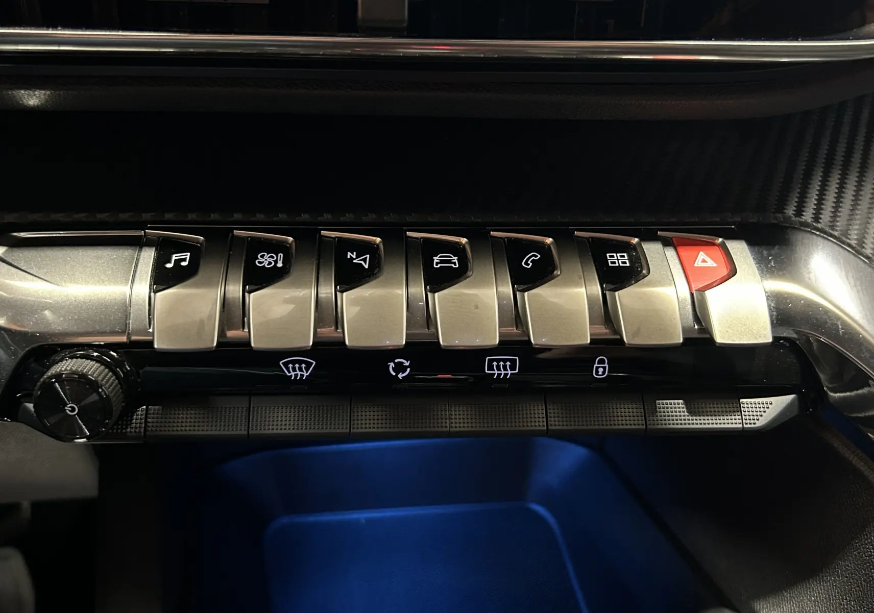 Gros plan sur la rangée de commandes métalliques du tableau de bord du Peugeot 5008 II Ph.2, éclairage intérieur bleu.