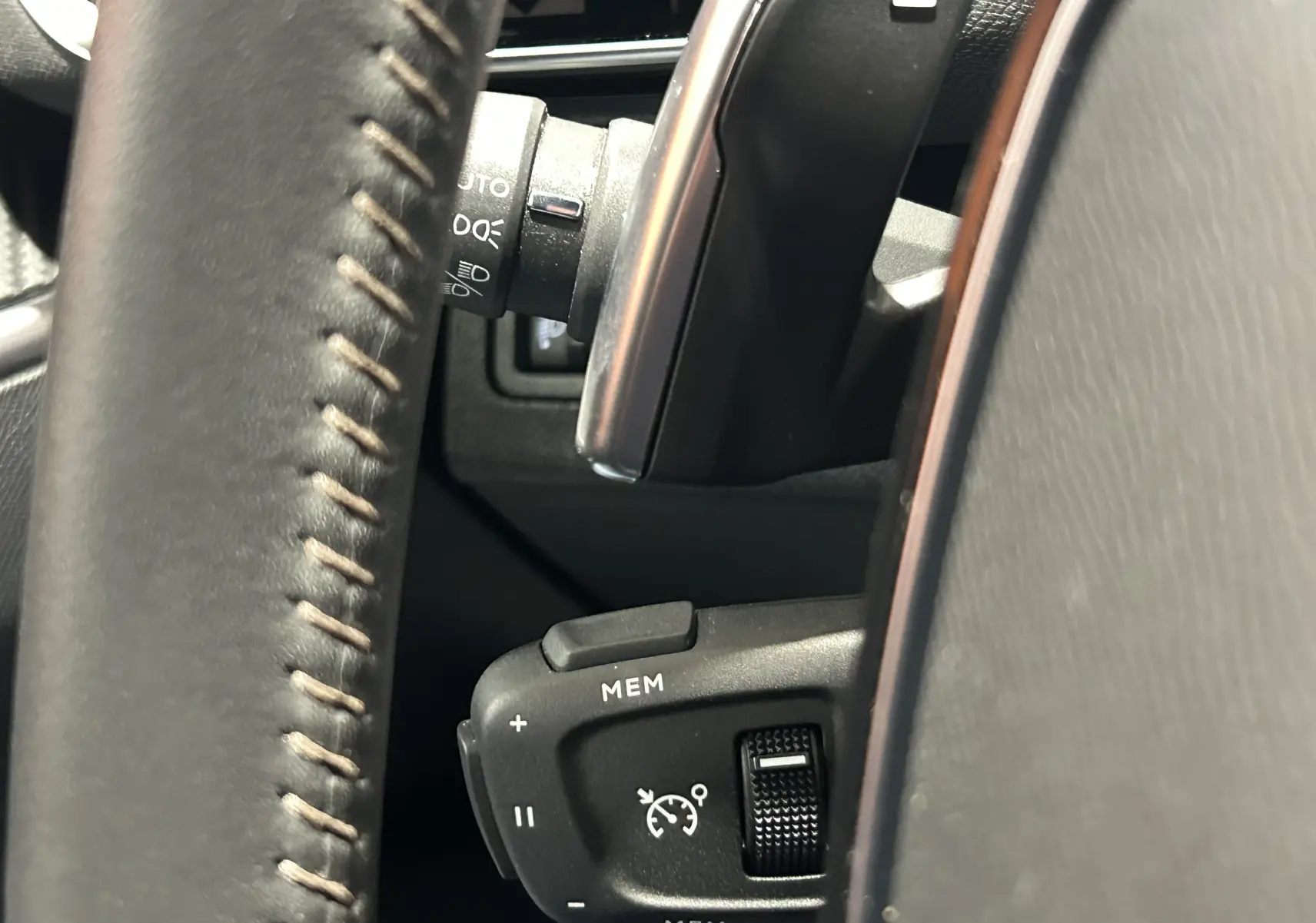 Gros plan sur la commande de régulateur de vitesse au volant en cuir du Peugeot 5008 Bleu Célèbes 2024.
