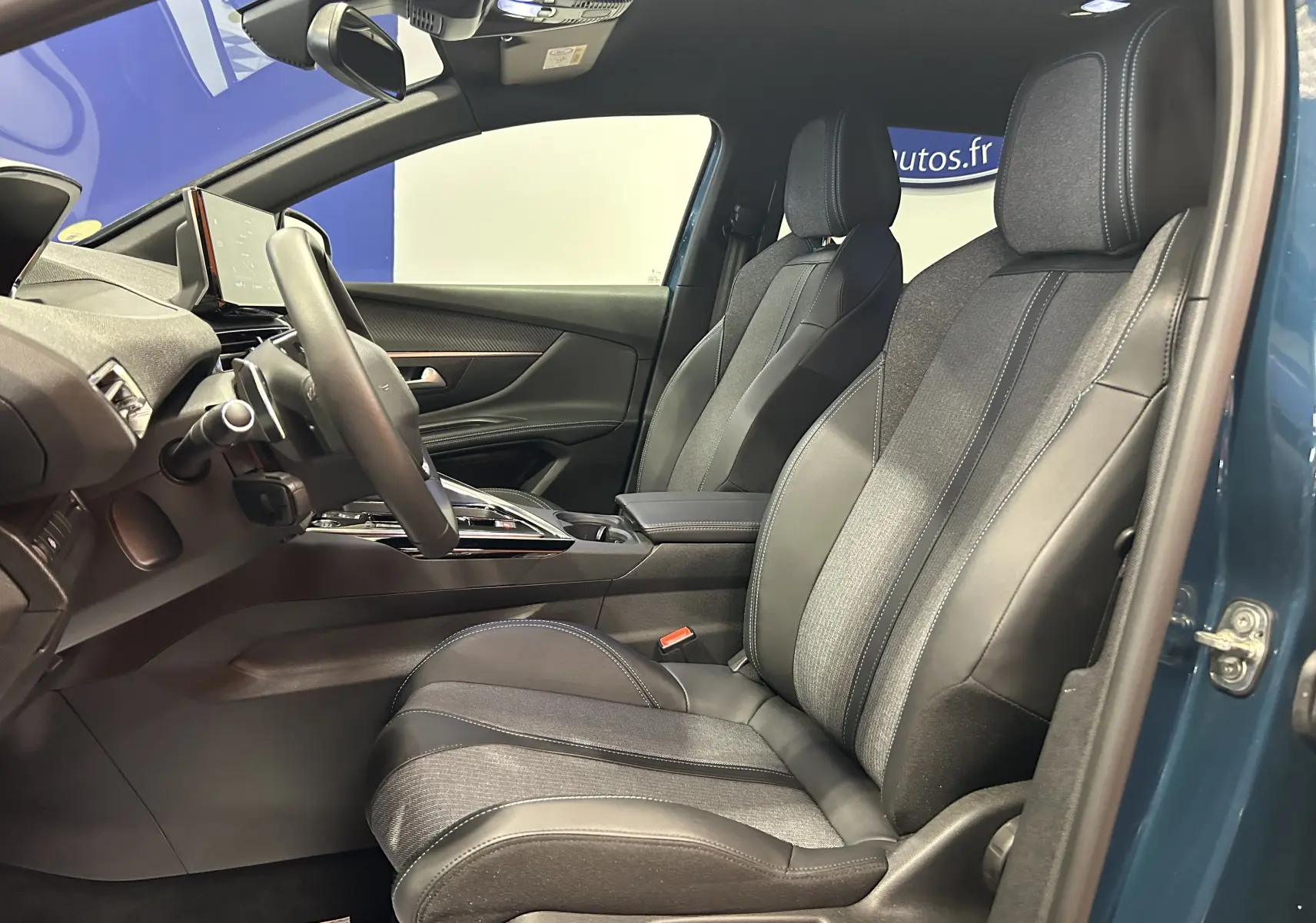 Vue intérieure côté gauche du Peugeot 5008 bleu Célèbes, mettant en valeur les sièges avant en cuir et tissu avec surpiqûres contrastantes.